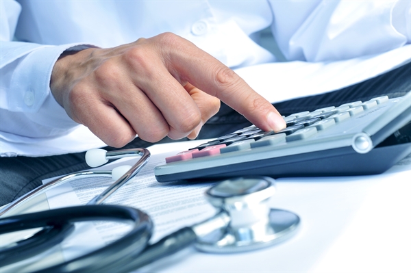 Doctor calculating medical expenses