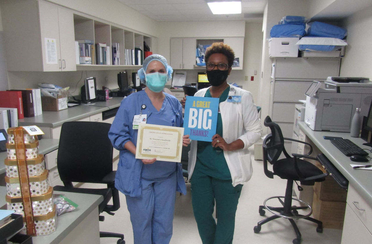 Healthcare professionals holding certificate and sign